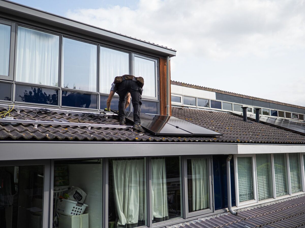A solar installer fitting panels on a home's rooftop